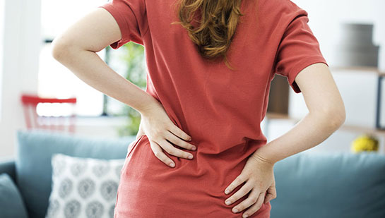 Woman holding lower back in pain before visiting Denver chiropractor