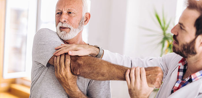 Elderly man receiving shoulder adjustment from Denver chiropractor