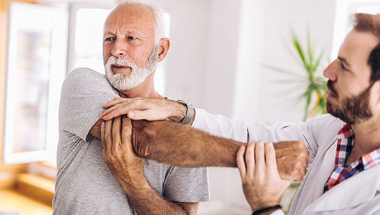 Elderly man receiving shoulder adjustment from Denver chiropractor